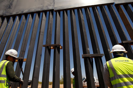 FILE PHOTO: Construction workers check a new section of bollard wall in Santa Teresa, New Mexico, as seen from the Mexican side of the border in San Jeronimo, on the outskirts of Ciudad Juarez, Mexico April 23, 2018. REUTERS/Jose Luis Gonzalez/File Photo