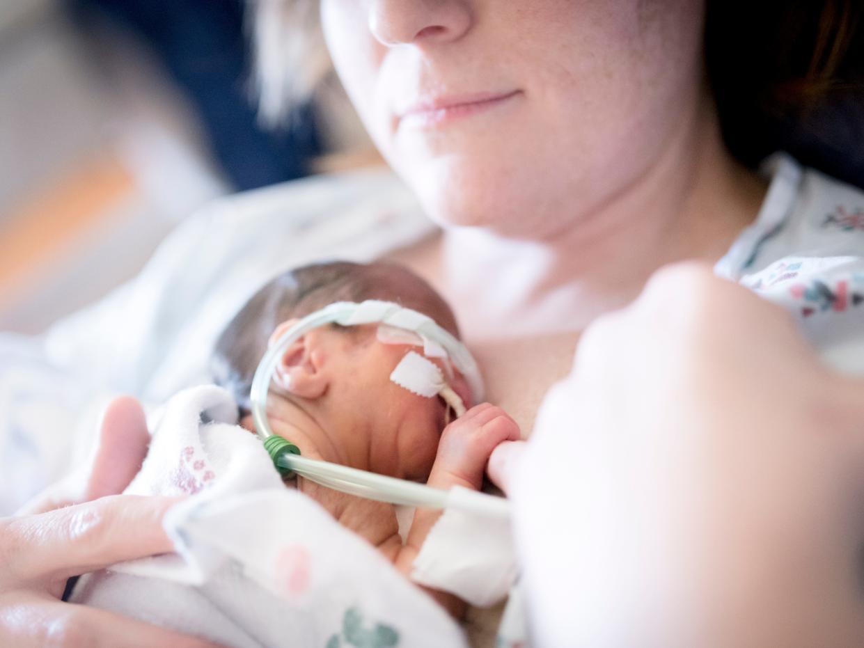 Premature Baby is held by mother