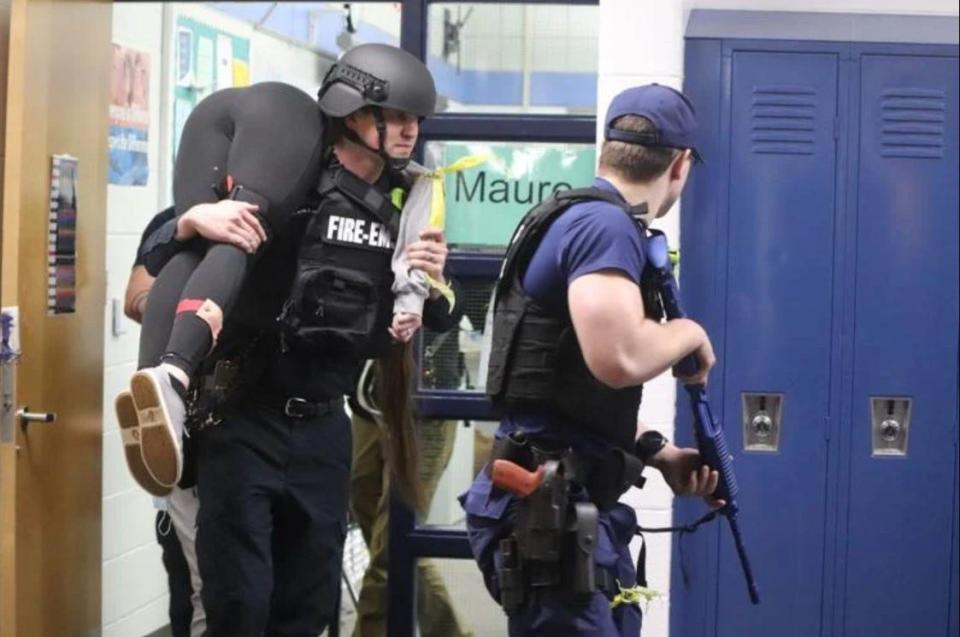 A local firefighter and Coast Guard officer rescue a victim while acting out a scenario during an active shooter training Monday night at Grand Haven High School.