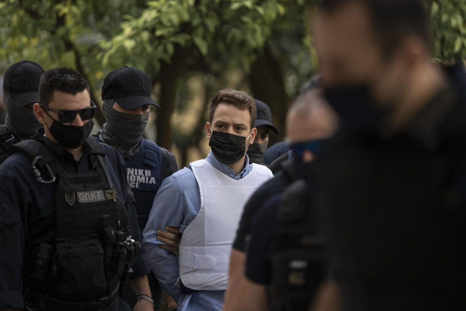 Helicopter pilot Babis Anagnostopoulos, center, escorted by police officers arrives to the prosecutor's office at a court to give evidence, in Athens, Tuesday, June 22, 2021. Anagnostopoulos was charged last Friday with the murder of his British-Greek wife, Caroline Crouch, 20, whose death he had initially claimed was caused by burglars during a brutal invasion of their home on the outskirts of Athens. (AP Photo/Petros Giannakouris)