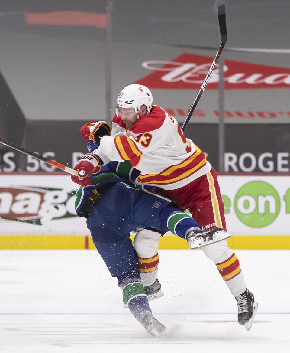 Calgary Flames' Sam Bennett, right, checks Vancouver Canucks' Nils Hoglander during the second period of an NHL hockey game Saturday, Feb. 13, 2021, in Vancouver, British Columbia. (Darryl Dyck/The Canadian Press via AP)