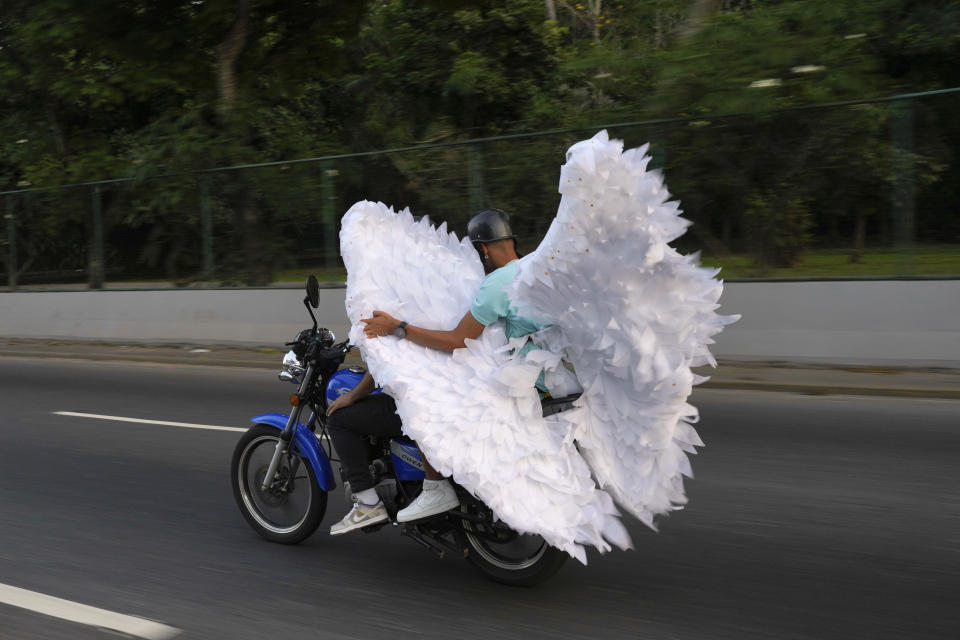 A duo transports a pair of angel wings on a motorcycle during carnival celebrations in Caracas, Venezuela, Monday, Feb. 12, 2024. (A P Photo/Ariana Cubillos)