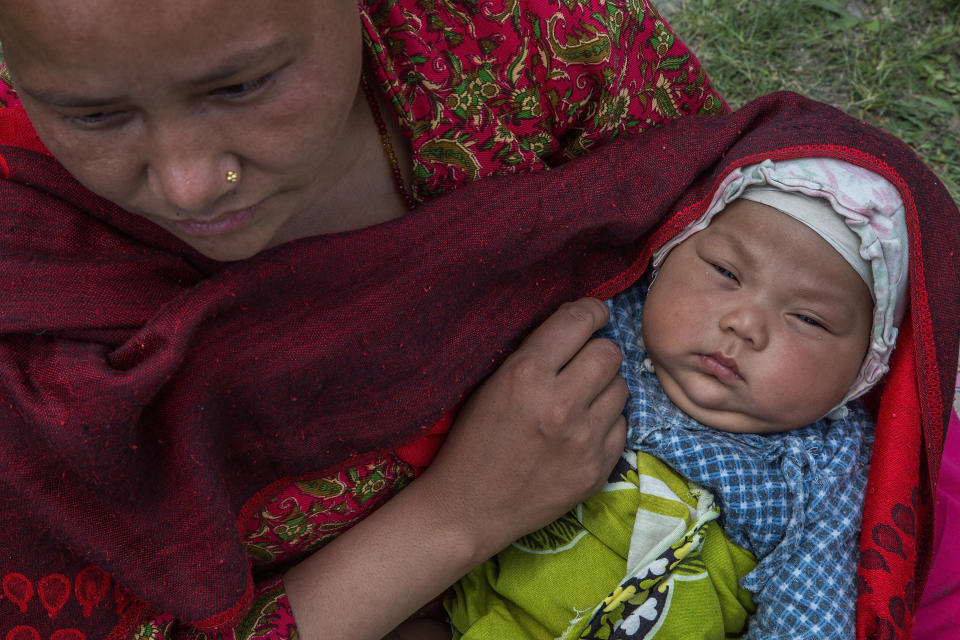 A mother holds her child in an evacuation area set up by the authorities in Tundhikel park on April 27, 2015 in Kathmandu, Nepal.  (Photo by Omar Havana/Getty Images)