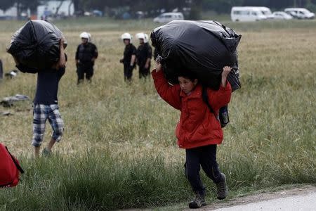 A refugee boy carries his belongings during a police operation at a refugee camp at the border between Greece and Macedonia, near the village of Idomeni, Greece, 24 May 2016 REUTERS/Yannis Kolesidis/Pool