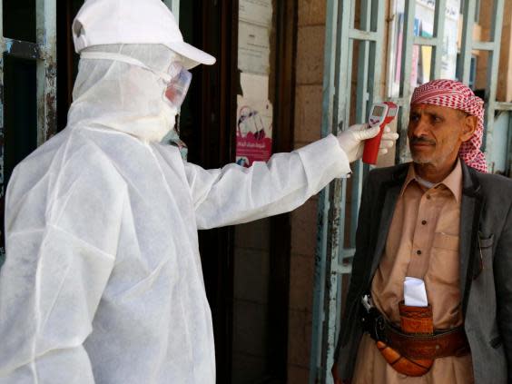 A medical worker measures the body temperature of a man at a state-run facility in Sana’a (Getty)