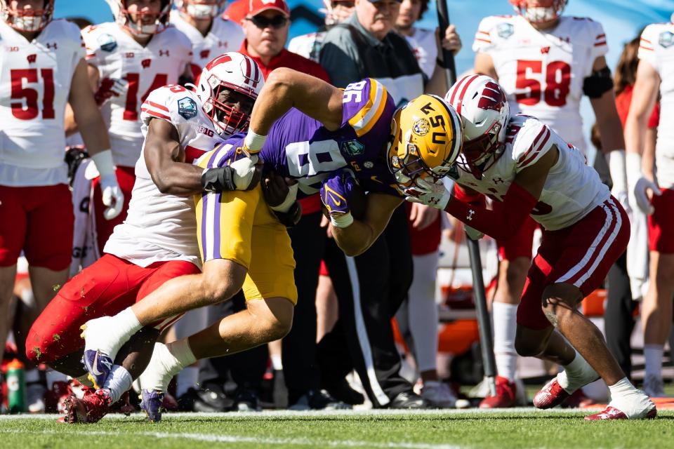 Jan 1, 2024; Tampa, FL, USA; Wisconsin Badgers cornerback Nyzier Fourqurean (10) and LSU Tigers defensive end Jake Ibieta (55) tackle LSU Tigers tight end Mason Taylor (86) at Raymond James Stadium. Mandatory Credit: Matt Pendleton-USA TODAY Sports