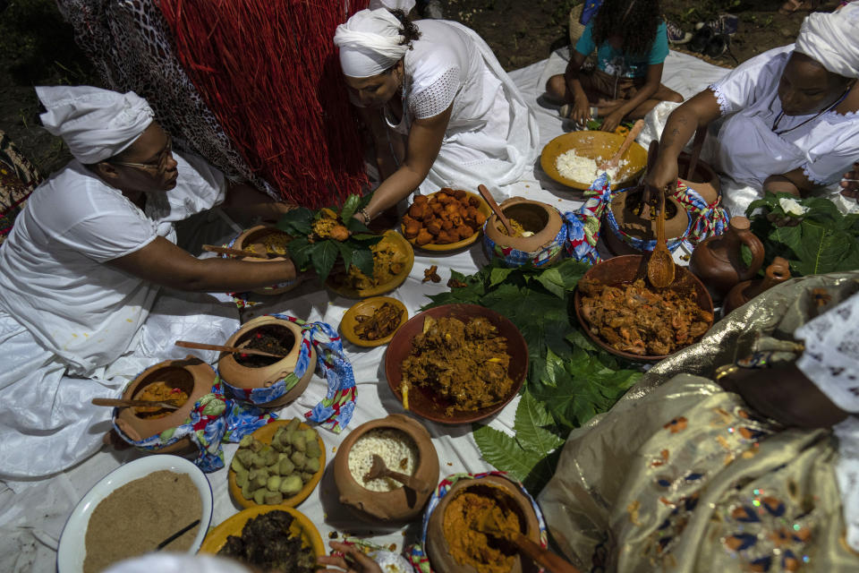 Women who practice Candomble serve Afro Brazilian dishes from clay pots during a ritual honoring the diety Obaluae, in a temple on the outskirts of Salvador, Brazil, Sunday, Sept. 18, 2022. Following a Yoruba blessing led by the temple’s matriarch, food was piled deep into makeshift bowls fashioned from leaves and shared around. (AP Photo/Rodrigo Abd)