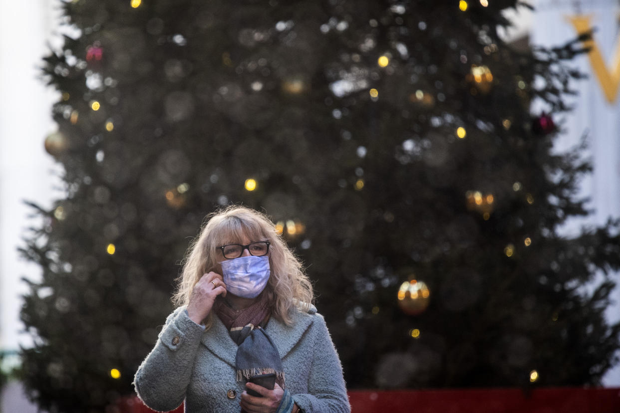 A woman wearing a face mask in front of a Christmas tree in the Leadenhall Market in London . (Photo by Victoria Jones/PA Images via Getty Images)