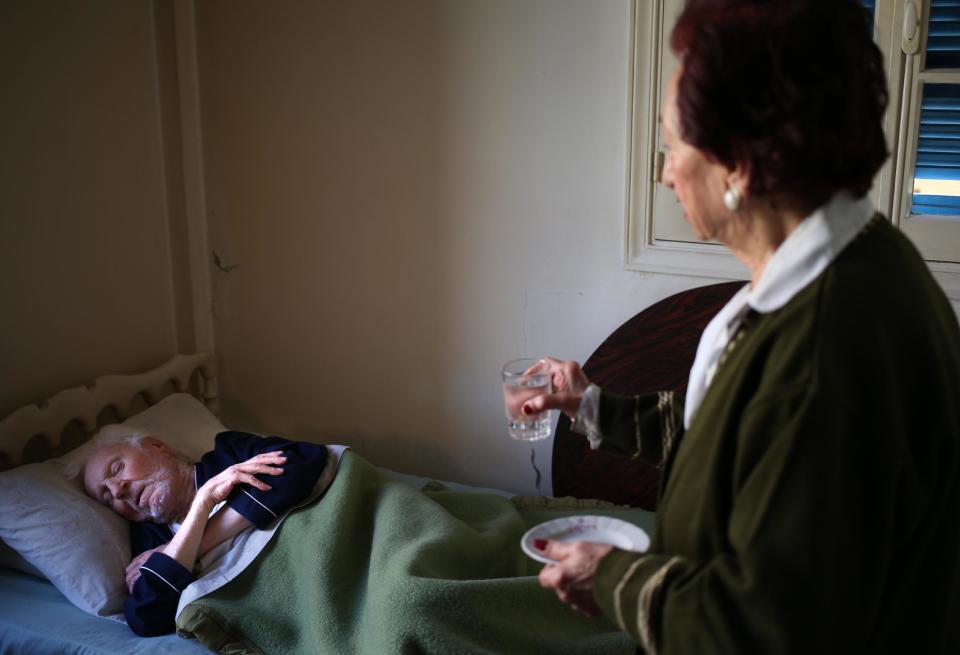 In this Thursday April 10, 2014 photo, Mary Mansourati, 82, whose son Dani went missing in Syria in 1992 at the age of 30, wakes up her elderly and gravely ill husband, Joseph, who has been bed-ridden for the past year, to give him a cup of water at her house, in Beirut, Lebanon. Their Dani is among an estimated 17,000 Lebanese still missing from the time of Lebanon’s civil war or the years of Syrian domination that followed. Syria’s civil war has added new urgency to the plight of their families, many of whom are convinced their loved ones are still alive and held in Syrian prisons, at risk of being lost or killed in the country’s mayhem. (AP Photo/Hussein Malla)