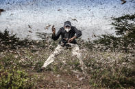 In this image released by World Press Photo, Thursday April 15, 2021, by Luis Tato for The Washington Post, part of a series titled Locust Invasion in East Africa which won third prize in the Nature Stories category, shows Henry Lenayasa, chief of the settlement of Archers Post, in Samburu County, Kenya, tries to scare away a massive swarm of locusts ravaging grazing area, on 24 April 2020. Locust swarms devastated large areas of land, just as the coronavirus outbreak had begun to disrupt livelihoods. (Luis Tato for The Washington Post, World Press Photo via AP)