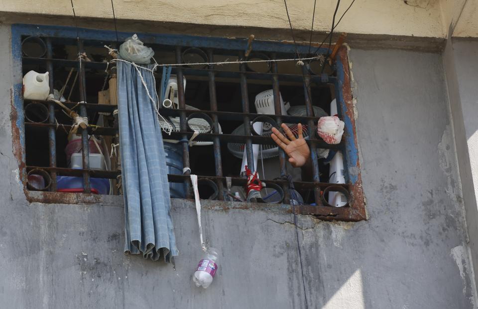 An inmate waves at the National Penitentiary in Port-au-Prince, Haiti, Sunday, March 3, 2024. Hundreds of inmates have fled Haiti's main prison after armed gangs stormed the facility overnight. (AP Photo/Odelyn Joseph)