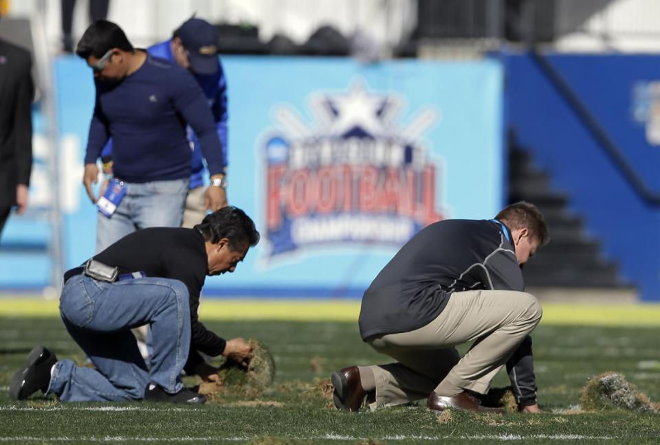 Stadium staff work on smoothing out the up-turned turf during a time out in play in the first half of the FCS championship NCAA college football game between North Dakota State and Towson, Saturday, Jan. 4, 2014, in Frisco, Texas. (AP Photo/Tony Gutierrez)