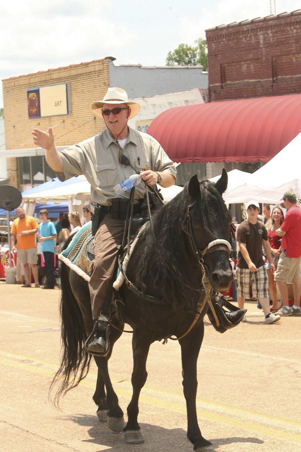 In this June 7, 2008 photo, Pickens County Sheriff David Abston waves from his horse during the Mule Day/Chicken Festival in Gordo, Ala. Court records show Abston was arrested Friday, June 14, 2019, and is pleading guilty to fraud and filing a false tax return. He is charged with scamming a food bank and his own church to pocket thousands under a law that let state sheriffs profit from feeding prisoners. (Michael Palmer/The Tuscaloosa News via AP)
