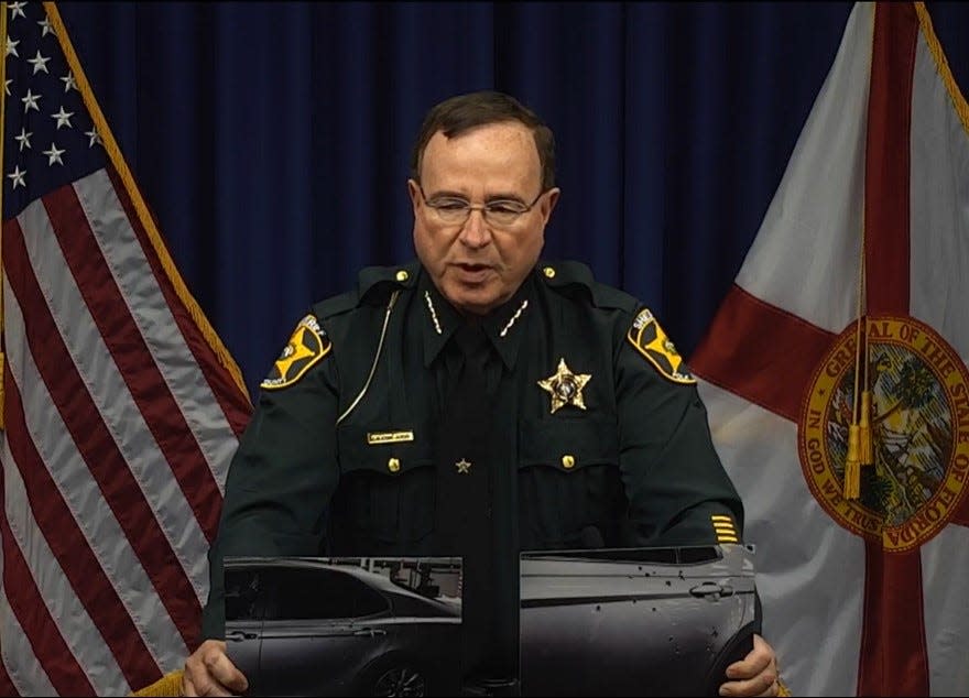 Polk County Sheriff Grady Judd holds up a photo of a Toyota Camry that was riddled with gunfire early Sunday morning.