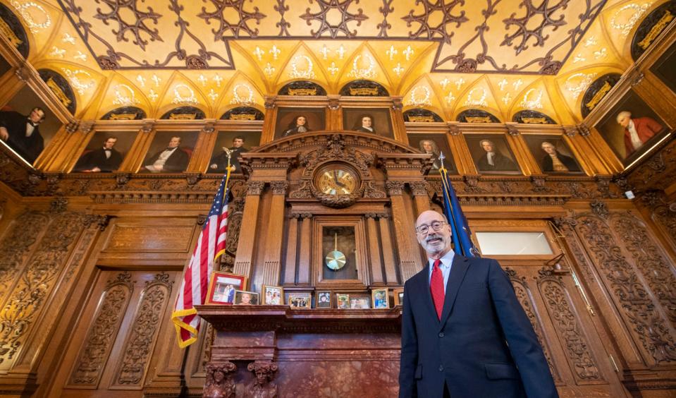 Governor Tom Wolf stands in the governor's office in the state capital building in Harrisburg on December 2, 2022. Surrounding him at the top of the room are portraits of former Pennsylvania governors.