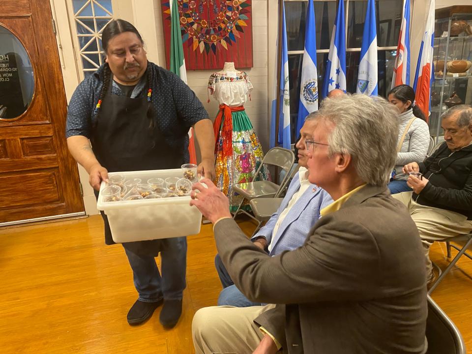 Tomahawk Alvarado (left) offers Indigenous foods to Jim Klein at the Instituto de Cultura Hispánica de Corpus Christi's "Decolonized Thanksgiving" event on Saturday.