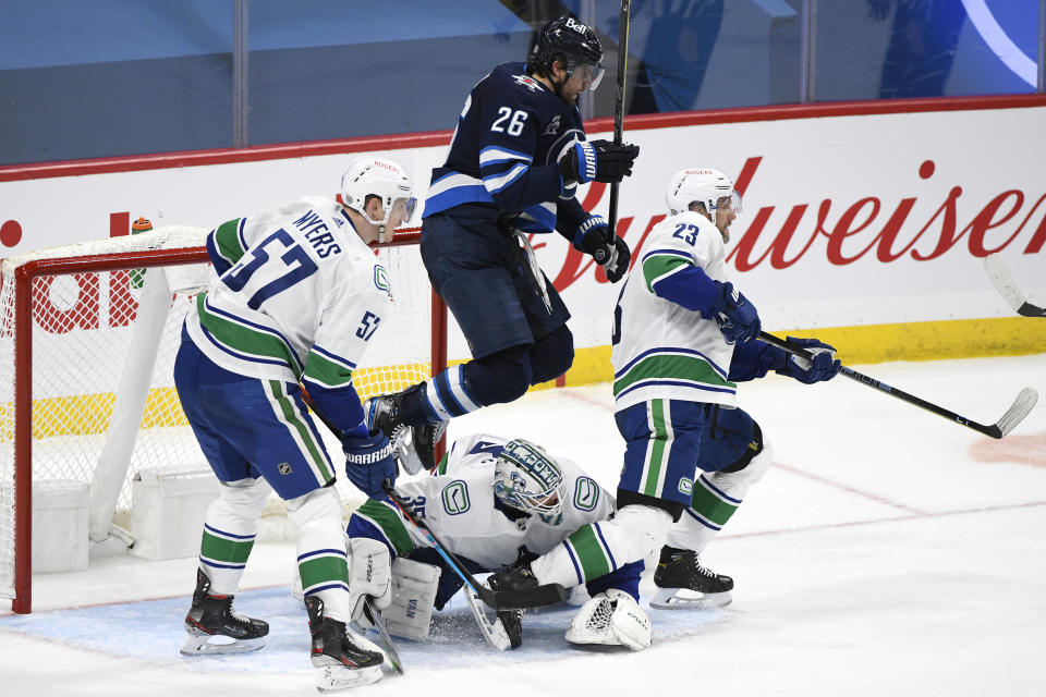 Winnipeg Jets' Blake Wheeler (26) jumps over Vancouver Canucks goaltender Thatcher Demko (35) during the third period of an NHL game in Winnipeg, Manitoba, Monday, May 10, 2021. (Fred Greenslade/The Canadian Press via AP)