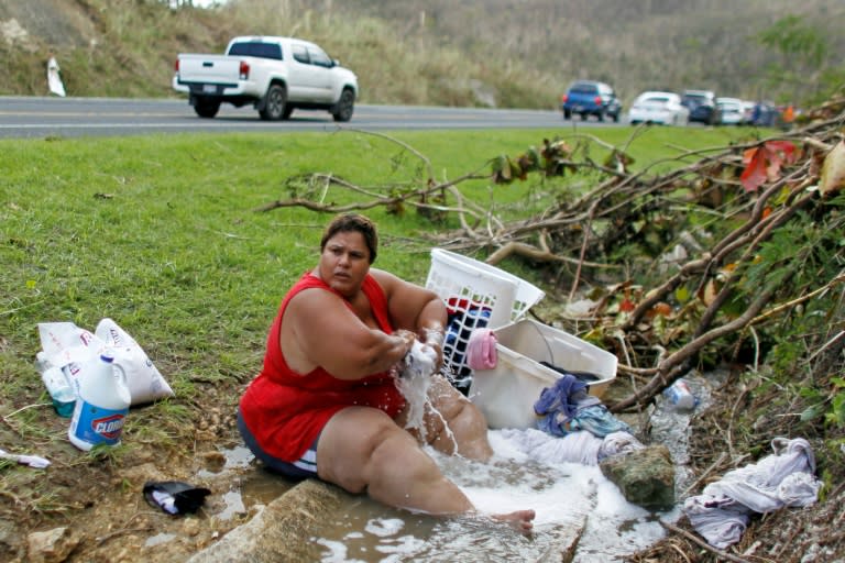 Iris Vazquez washes clothing at an open road drainage west of San Juan, Puerto Rico following the passage of Hurricane Maria