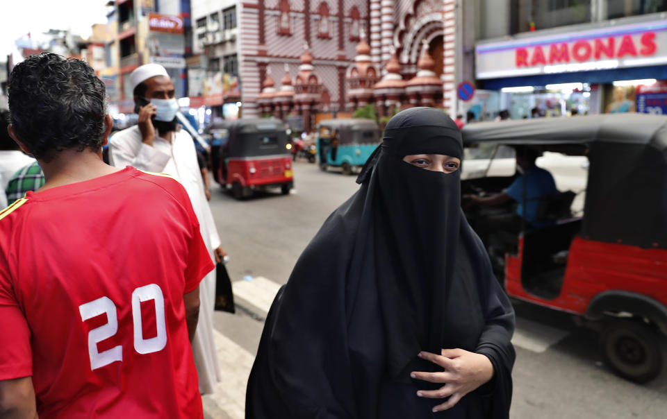 A burqa clad Sri Lankan Muslim woman walks in a street of Colombo, Sri Lanka, Saturday, March 13, 2021. Sri Lanka on Saturday announced plans to ban the wearing of burqas and said it would close more than 1,000 Islamic schools known as madrassas, citing national security. (AP Photo/Eranga Jayawardena)