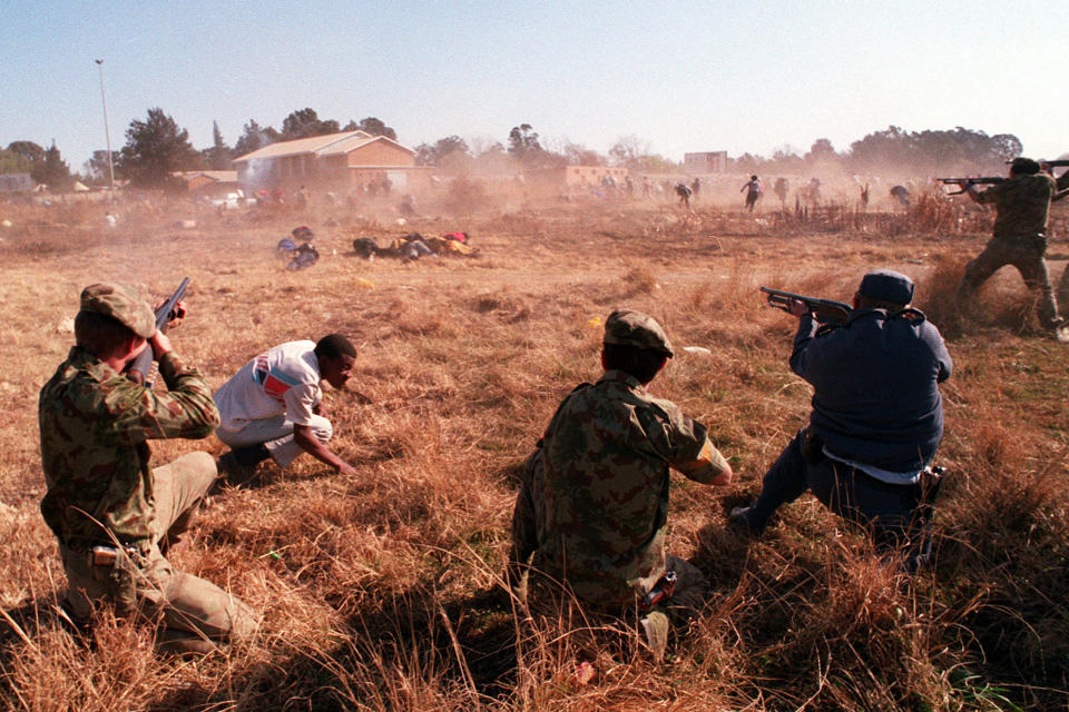 FILE - Police fire at fleeing protesters June 20, 1992, in Boipatong, South Africa. South Africa is engrossed in debate over the legacy of apartheid's last president, de Klerk, who died at 85 and is to be buried Sunday, Nov 21, 2021. Some people want to remember de Klerk as the liberator of Nelson Mandela, but others say he was responsible for racist murders. (AP PHoto/Greg Marinovich, File)