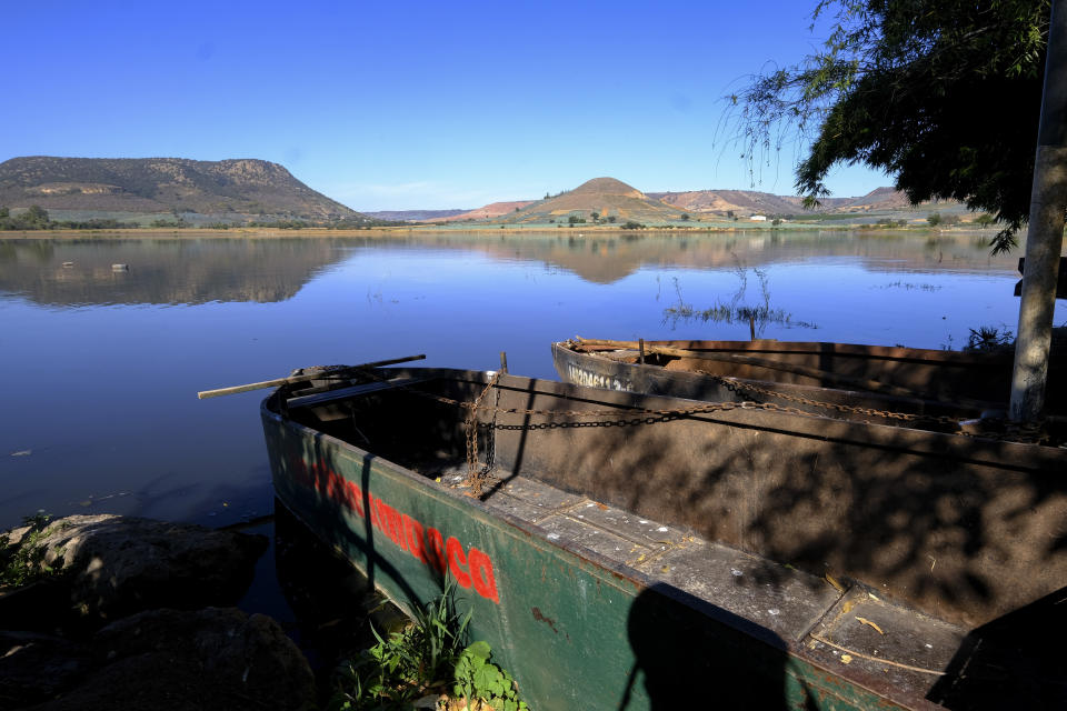 Boats of a fishermen's cooperative lay beached on the shore of the San Onofre reservoir in Ayotlan, Mexico, Thursday, Dec. 9, 2021. Authorities determined that millions of liters of a residue known as vinasse created in tequila's distillation, spilled into the Las Animas creek and flowed into the reservoir. (AP Photo/Refugio Ruiz)