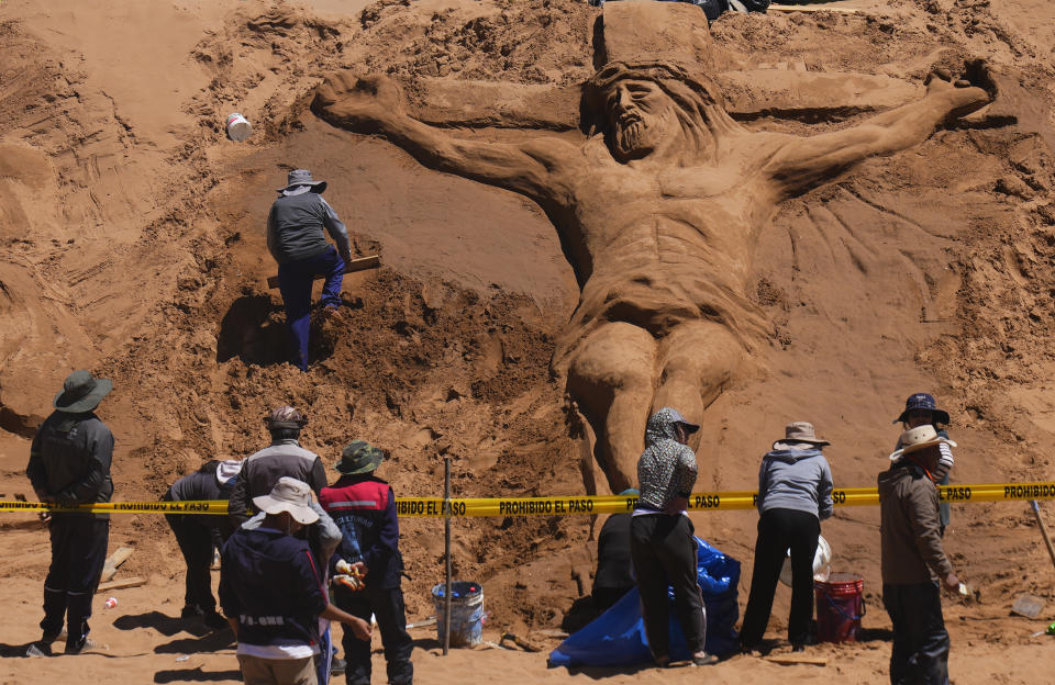 An artist works on a sand sculpture depicting Jesus Christ on a cross as part of Holy Week celebrations, in Los Arenales de Cochiraya, on the outskirts of Oruro, Bolivia, Good Friday, March 29, 2024. Artists gathered for the annual Holy Week event in the highland region, building sand sculptures based on Bible stories. (AP Photo/Juan Karita)