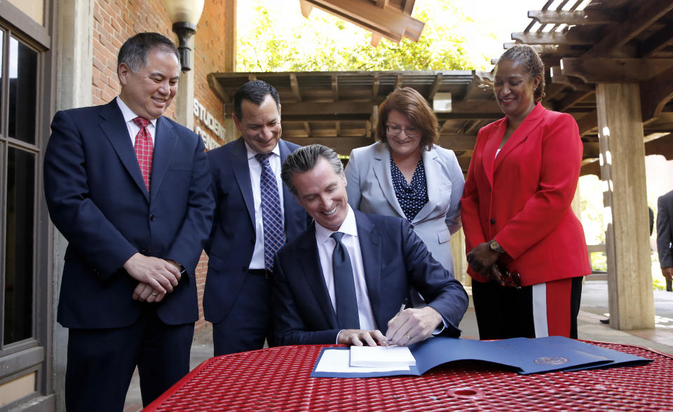 Gov. Gavin Newsom signs one of the budget trailer bills at Sacramento City College in Sacramento, Calif., Monday, July 1, 2019. Looking on, from left, is Assembly Budget Chairman Phil Ting, D-San Francisco, Assembly Speaker Anthony Rendon, of Lakewood, second from left, State Senate President Pro Tem Toni Atkins, of San Diego, third from left and Senate Budget Chairwoman Holly Mitchell, D-Los Angeles, right.(AP Photo/Rich Pedroncelli)