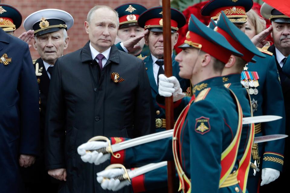 People in uniforms march past a line of people.