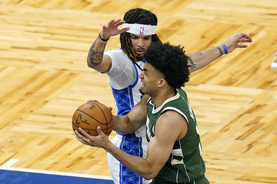 Milwaukee Bucks forward Jordan Nwora, right, goes past Orlando Magic guard Cole Anthony on his way to the basket during the first half of an NBA basketball game, Sunday, April 11, 2021, in Orlando, Fla. (AP Photo/John Raoux)