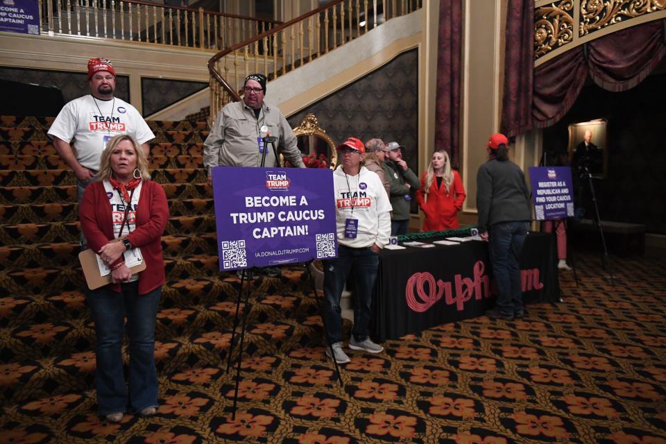 Trump presidential campaign volunteers surround a table and sign encouraging rally attendees to sign up as a caucus captain at a rally held by the former president at the Orpheum Theatre in Sioux City, Iowa on Sunday, Oct. 29, 2023.