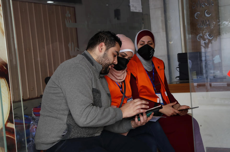 Members of Central Elections Commission's filed teams check to register a local resident to the electoral roll, at the main road of Gaza City, Feb. 10, 2021. Palestinian poll workers fanned out across the Gaza Strip on Wednesday, where they found voters eager to register ahead of elections that could serve as the first referendum on Hamas' rule since the militant group seized power more than a decade ago. (AP Photo/Adel Hana)