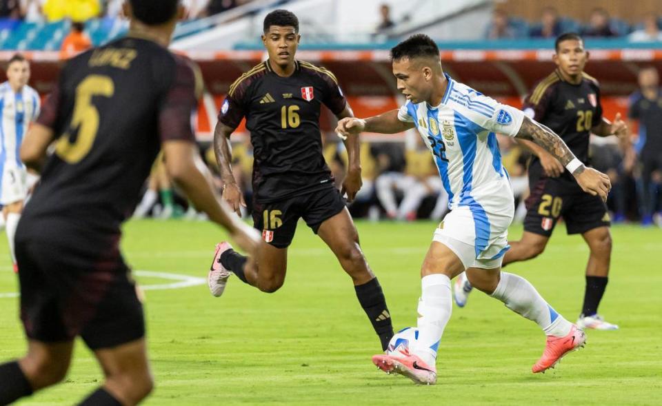 Argentina forward Lautaro Martínez (22) looks to pass the ball as Peru midfielder Wilder Cartagena (16) defends in the first half of their CONMEBOL Copa America 2024 group A soccer match at Hard Rock Stadium on Saturday, June 29, 2024, in Miami Gardens, Fla.