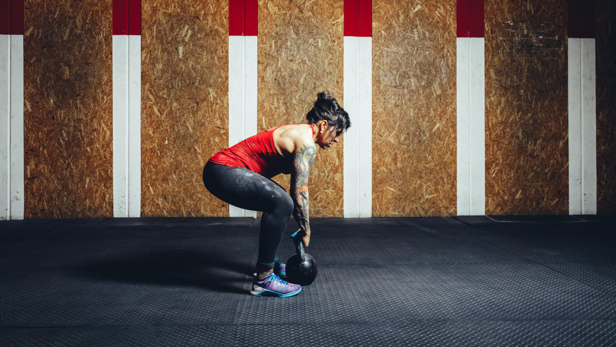  Woman performing deadlift with kettlebell. 