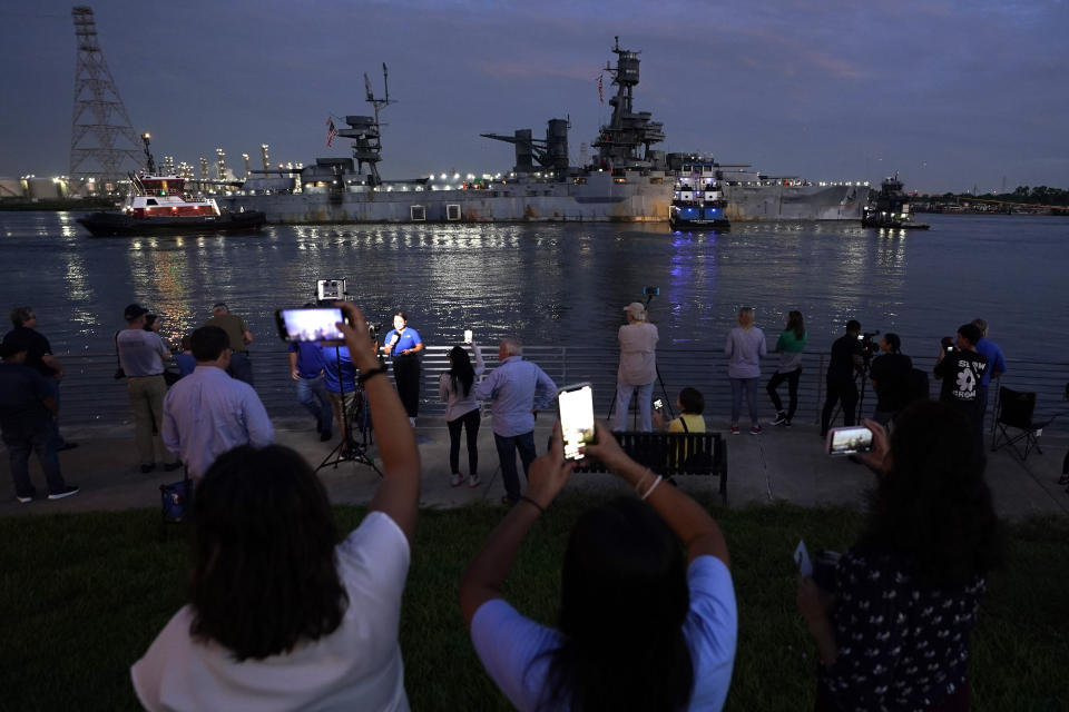 People watch as the USS Texas is moved into position to be towed, Wednesday, Aug. 31, 2022, in La Porte, Texas. The vessel, which was commissioned in 1914 and served in both World War I and World War II, is being towed down the Houston Ship Channel to a dry dock in Galveston where it will undergo an extensive $35 million repair. (AP Photo/David J. Phillip)