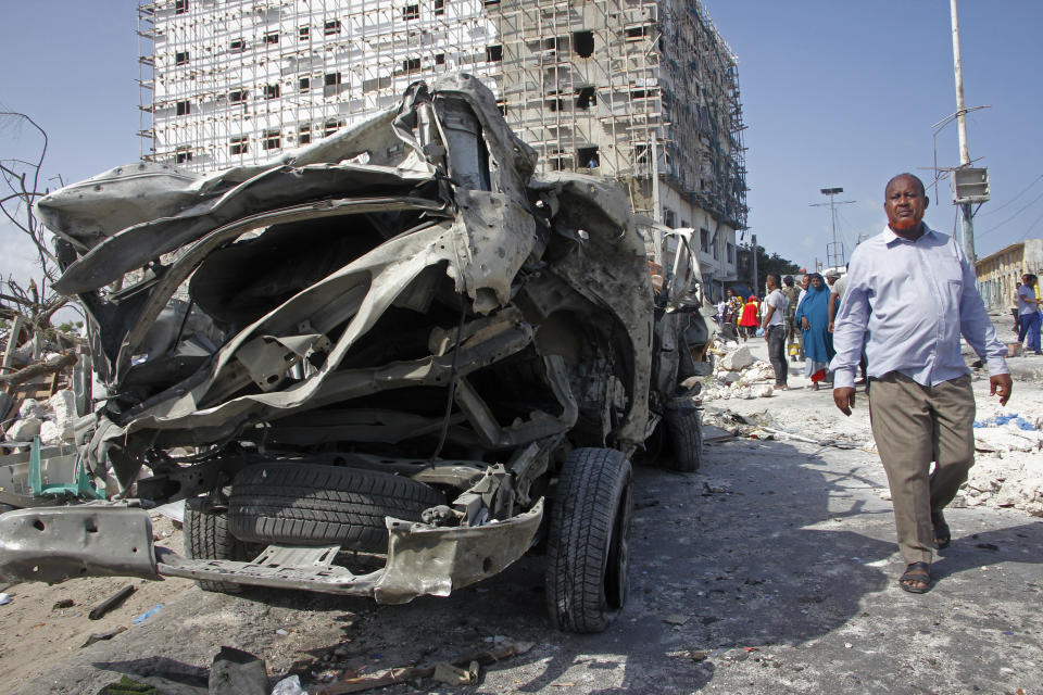 A man walks past the wreckage of an official vehicle that was destroyed in a bomb attack in the capital Mogadishu, Somalia, Saturday, June 15, 2019. (AP Photo/Farah Abdi Warsameh)