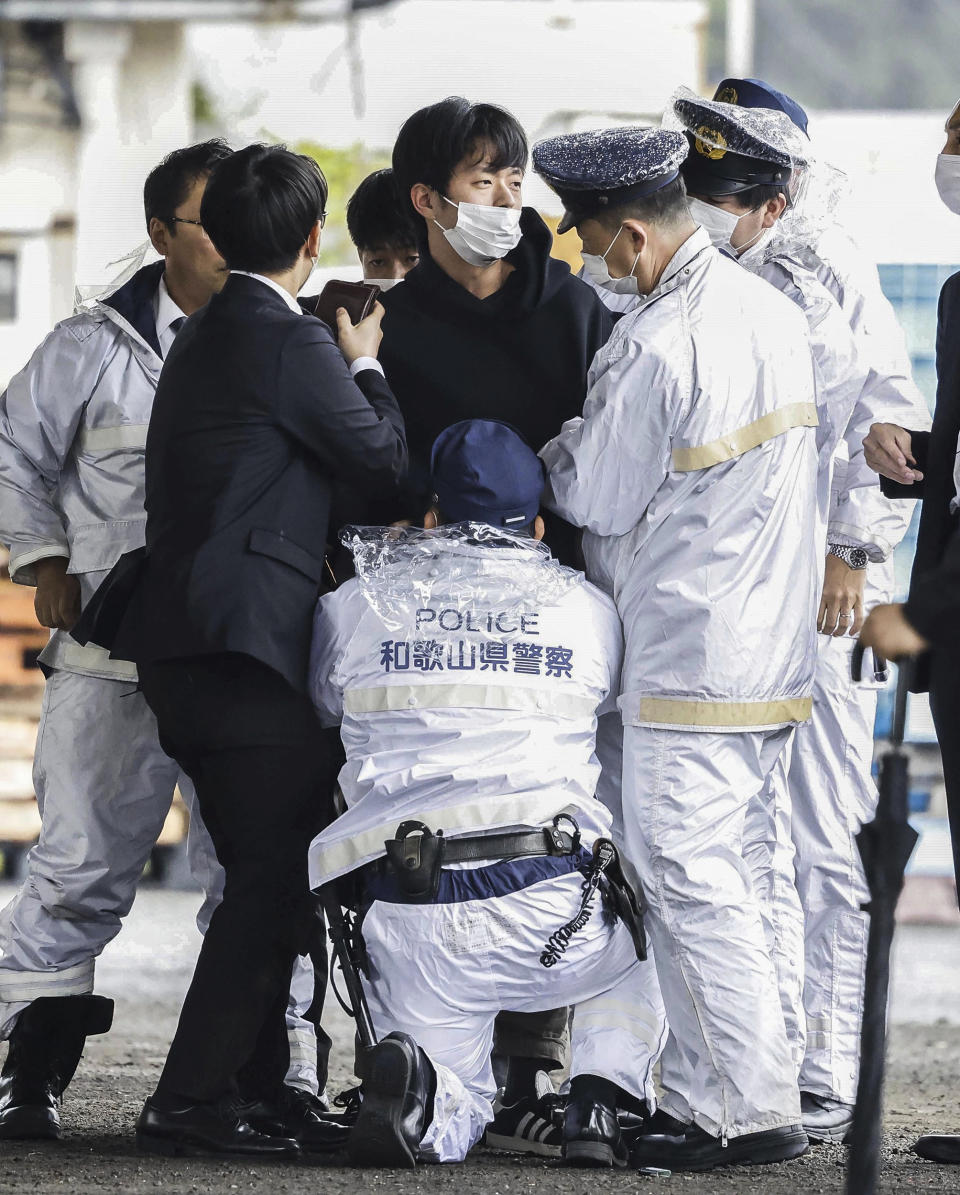 Image: A man, center, who threw what appeared to be a smoke bomb, is caught at a port in Wakayama, western Japan on April 15, 2023. (Kyodo News via AP)