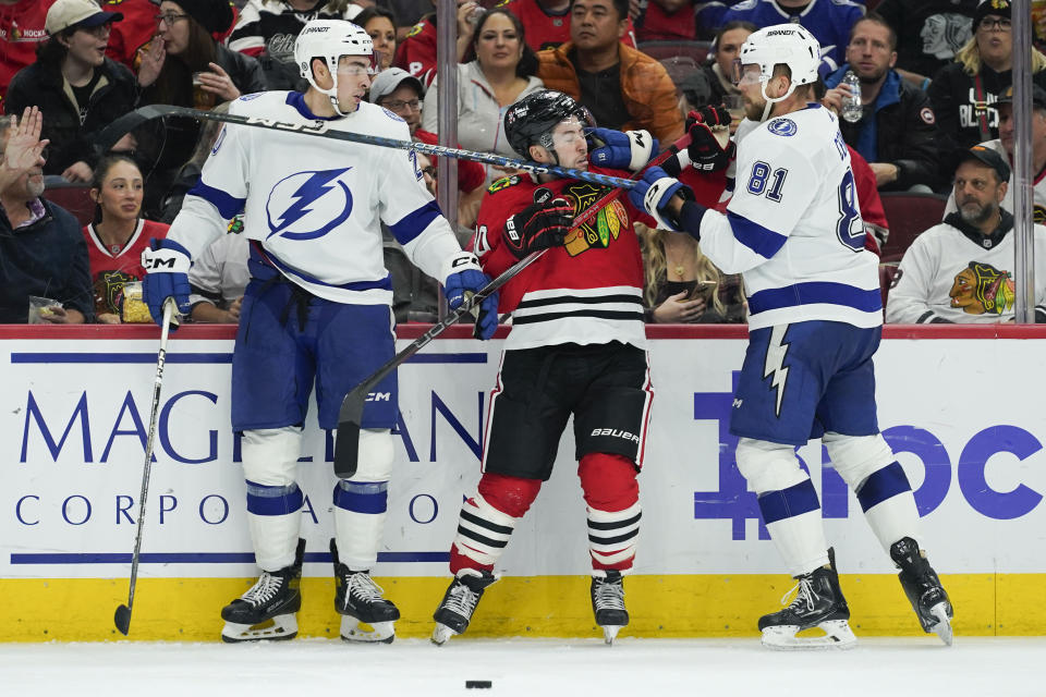 Tampa Bay Lightning defenseman Erik Cernak, right, shoves Chicago Blackhawks center Tyler Johnson, center, during the second period of an NHL hockey game Thursday, Nov. 16, 2023, in Chicago. (AP Photo/Erin Hooley)