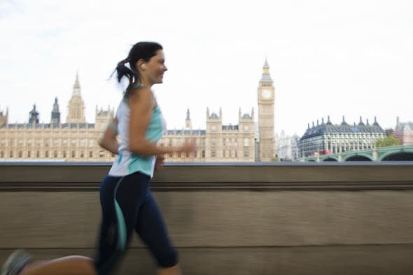 UK, London, Woman running in front of Westminster skyline