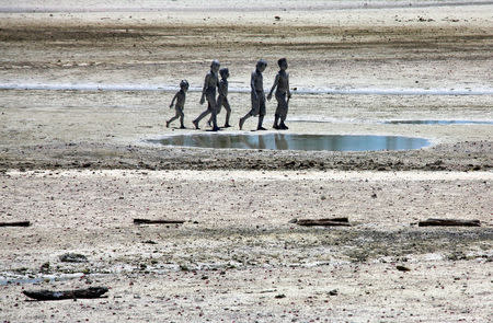 Young boys covered in reef mud walk towards their homes in the village of Ambo located on South Tarawa in the central Pacific island nation of Kiribati May 25, 2013. REUTERS/David Gray