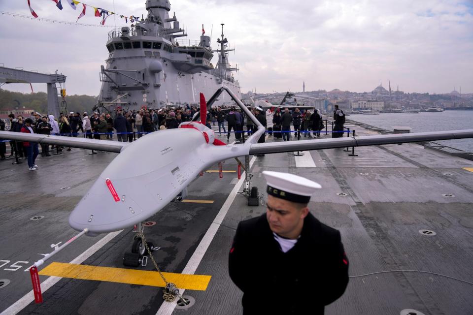 A navy soldier stands next to an unmanned combat aerial vehicle (UCAV) Bayraktar TB3 on board the Turkish amphibious assault ship TCG Anadolu L400, anchored in Istanbul, Turkey, on April 20, 2023.