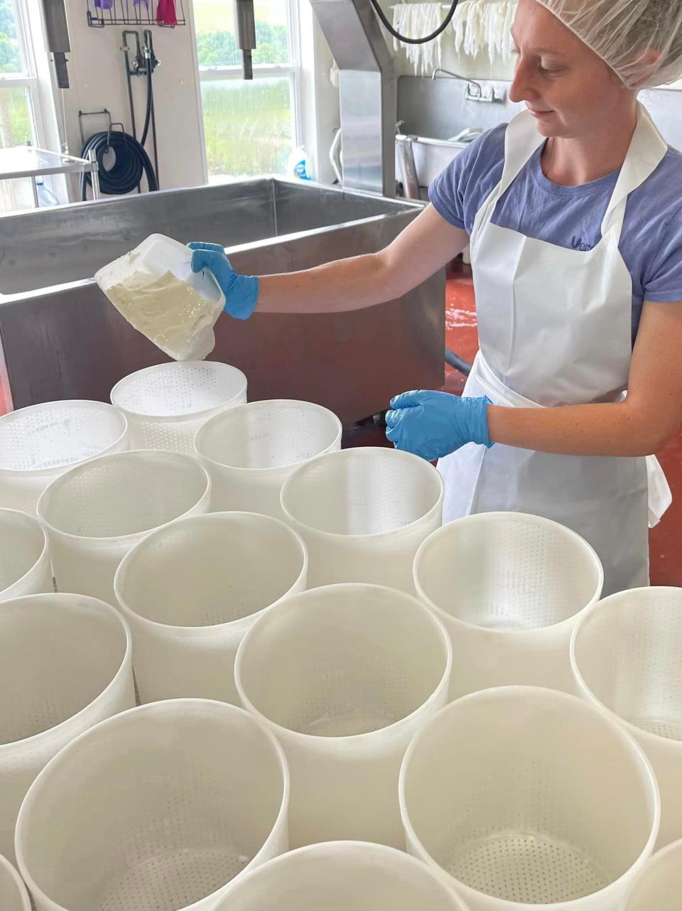 In this picture taken in July 2022 at Calkins Creamery, Maggie is filling molds with their Georgic cheese.