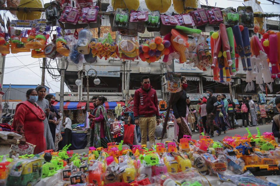 Indians, most of them, wearing face masks as a precautionary measure against the coronavirus walk at a Sunday market in Jammu, India, Sunday, Nov.22, 2020. (AP Photo/Channi Anand)