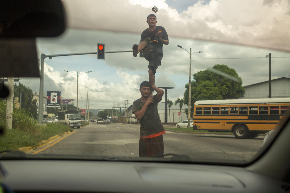 Two street jugglers perform on a corner for money in San Pedro Sula, Honduras on Nov. 28, 2019. The city's criminal life is dominated by two street gangs formed decades earlier in Latino enclaves of Los Angeles, spreading southward as gang members were deported. Today, MS-13 and Mara 18 are the most powerful and feared gangs in Central America, and have operations that reach from Mexico to the U.S. to Europe. (AP Photo/Moises Castillo)