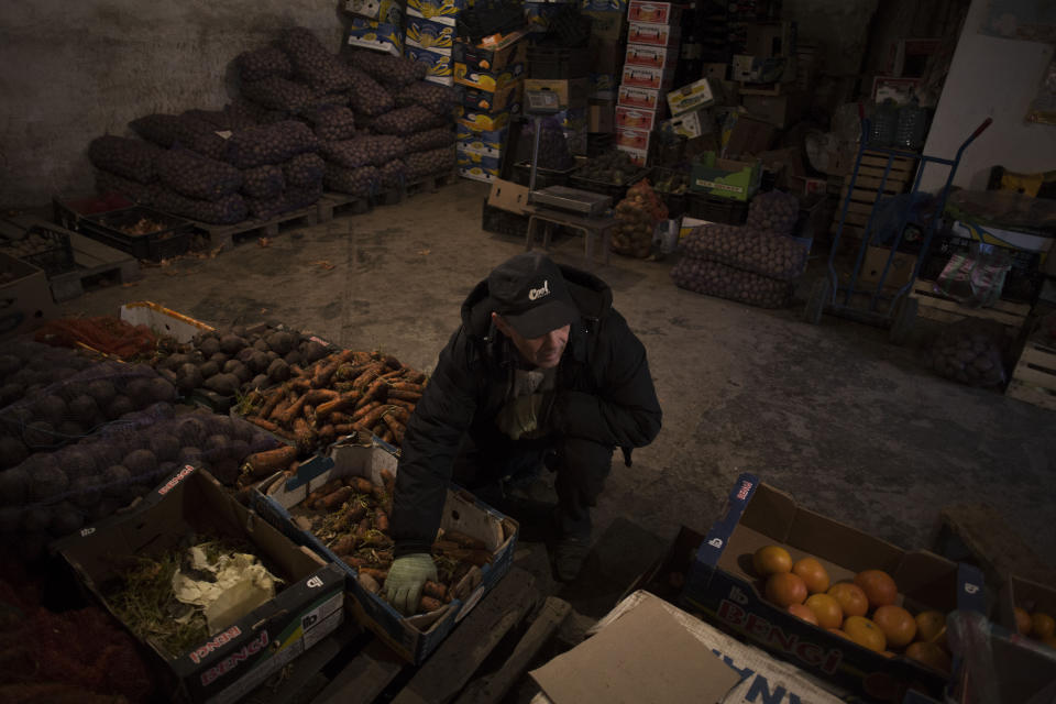 FILE - In this Sunday, March 16, 2014 file photo a Tatar man works in a fruit warehouse within a market in Bakhchisaray, Crimea. Despite the pebble beaches and cliff-hanging castles that made Crimea famous as a Soviet resort hub, the Black Sea peninsula has long been a corruption-riddled backwater in economic terms. The Kremlin, which decided to take the region from Ukraine after its residents voted in a referendum to join Russia, has begun calculating exactly what it will cost to support Crimea's shambolic economy, which one Russian minister described as "no better than Palestine." (AP Photo/Manu Brabo, File)