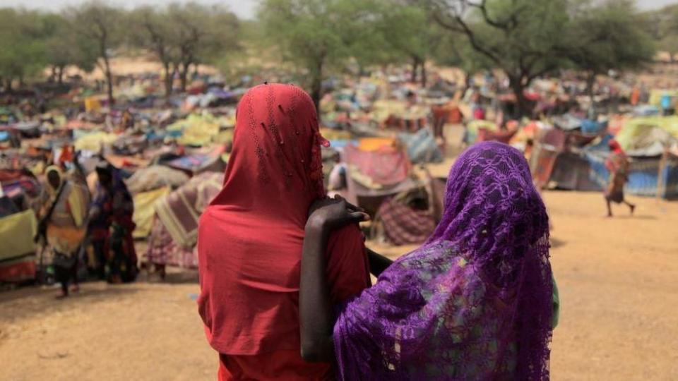 Dos mujeres de espaldas ven un campamentos de refugiados