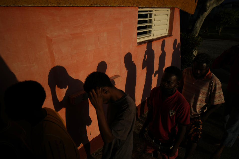 The shadows of Haitian migrants are cast on a wall as they wait to receive food at a tourist campground in Sierra Morena, in the Villa Clara province of Cuba, Wednesday, May 25, 2022. A vessel carrying more than 800 Haitians trying to reach the United States wound up instead on the coast of central Cuba, government news media said Wednesday. (AP Photo Ramon Espinosa)