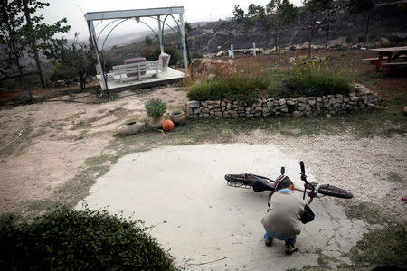 An Israeli boy plays with a bicycle in the Jewish settler outpost of Amona in the West Bank, November 22, 2016. REUTERS/Ronen Zvulun