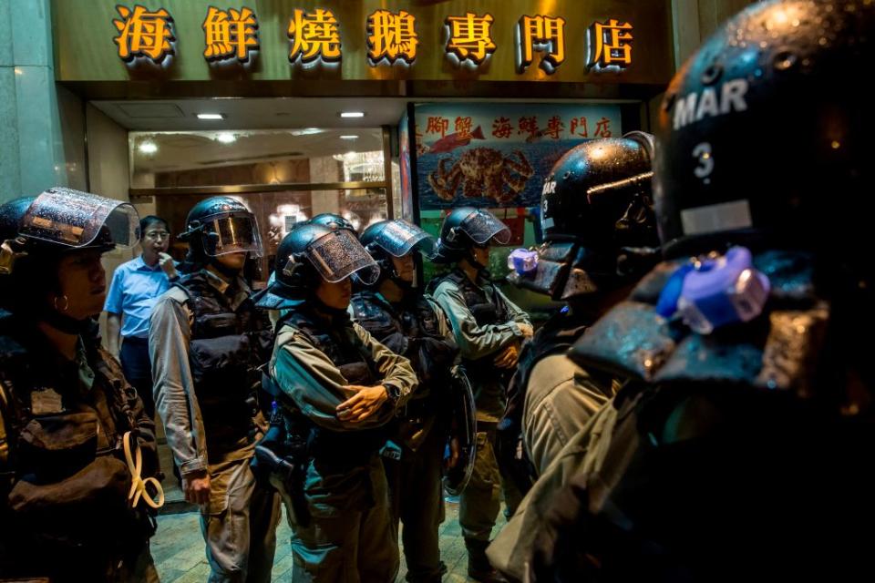 Riot police stand in front of a restaurant while patrolling after an anti-government rally in Hong Kong on August 18, 2019. | Isaac Lawrence—AFP/Getty Images