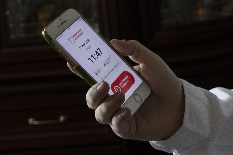 In this May 27, 2020, photo, Vladimir Perevalov shows a Social Monitoring app installed on his smartphone in his apartment in Shcherbinka, outside Moscow, Russia. The app is designed to track Moscow's quarantined coronavirus patients and rolled out by city officials in April, but users complain it is full of glitches and has imposed fines on them wrongly. Perevalov said he was fined three times for $168. (AP Photo/Pavel Golovkin)