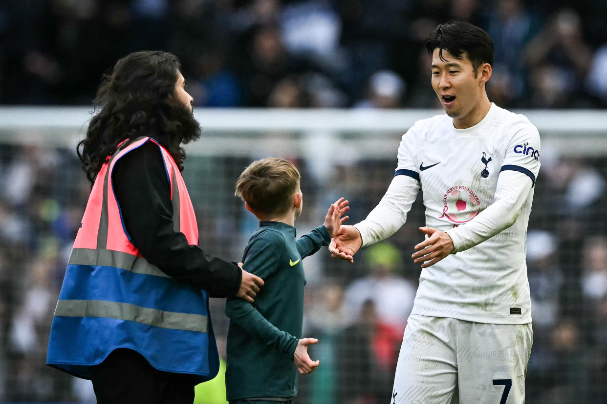 Tottenham Hotspur forward Son Heung-Min greets a young pitch invader at the end of their English Premier League match against Luton Town.